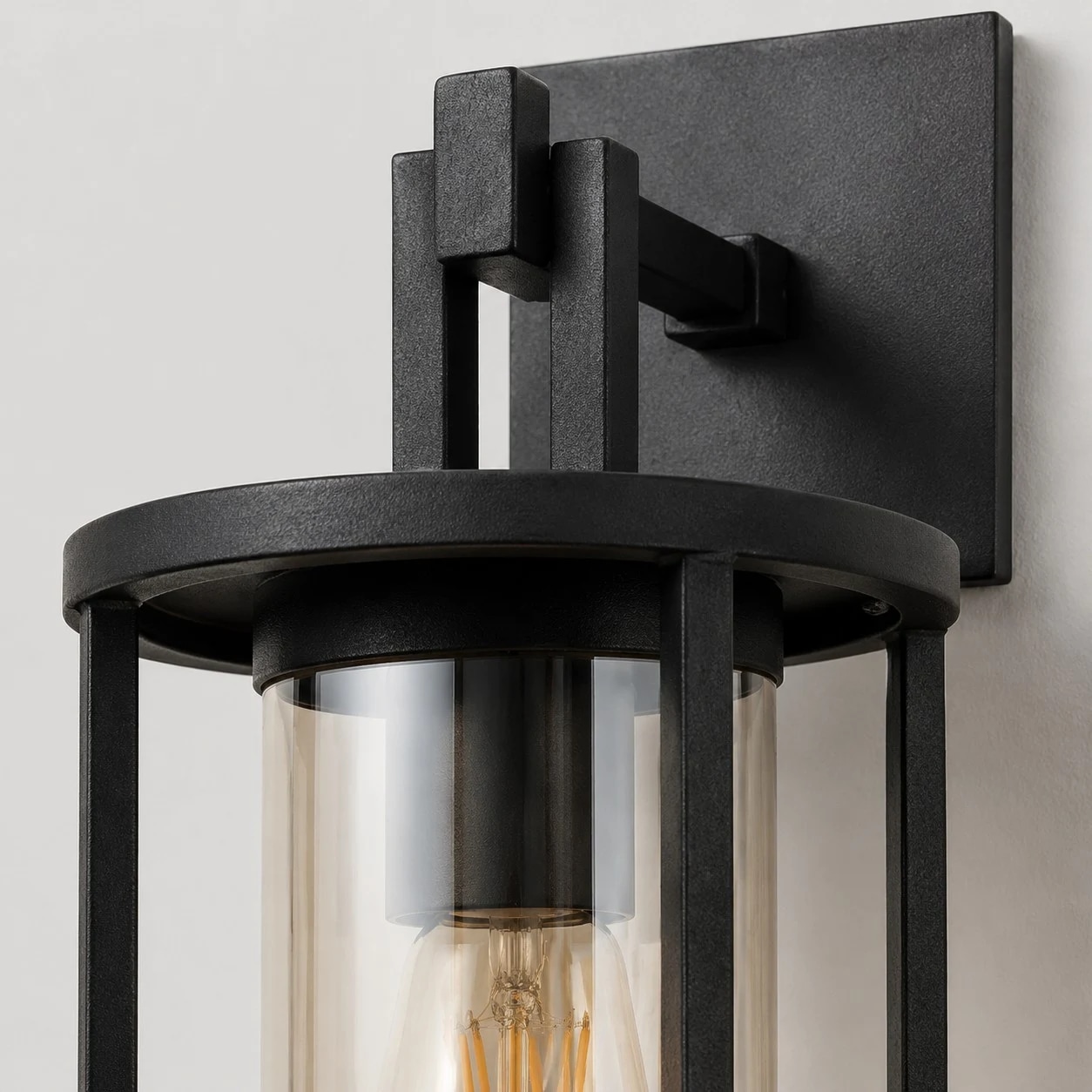 Close-up of black wall lantern arm, top ring, and amber glass shade